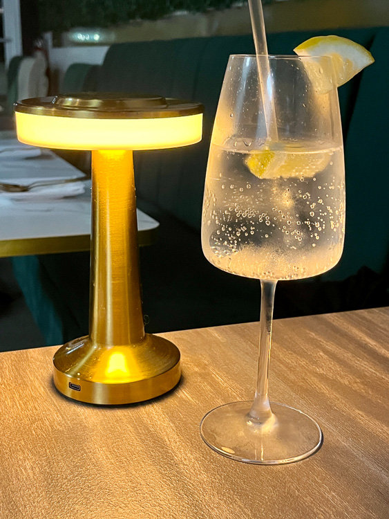 gold lamp next to glass drink with lemon